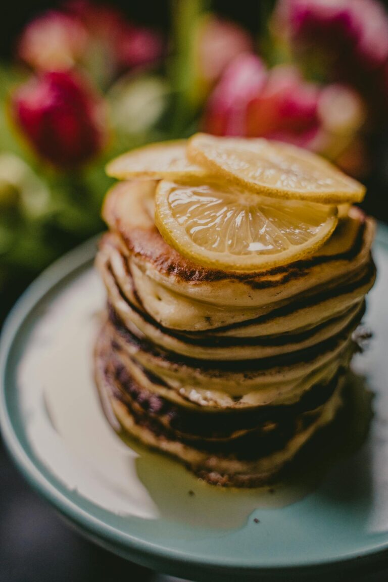 Delicious stack of pancakes topped with lemon slices on a stylish plate.